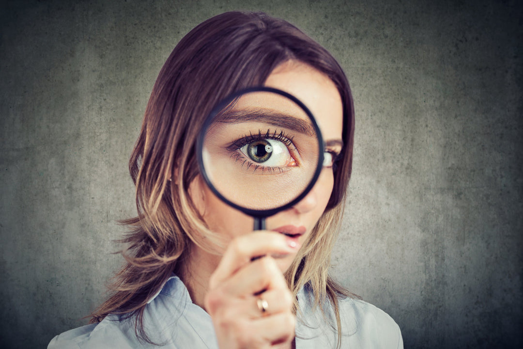 Femme tenant une loupe agrandissant son œil