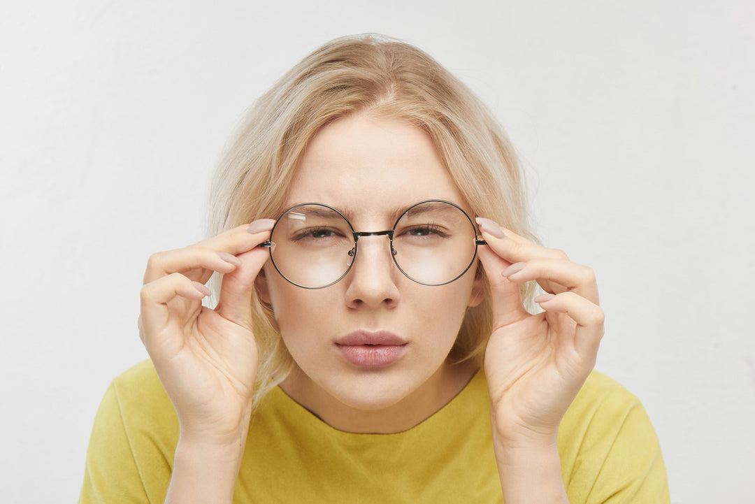 Femme plissant les yeux en ajustant ses lunettes rondes