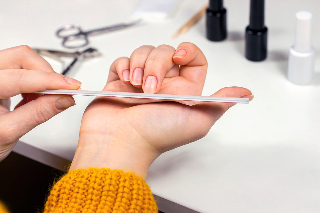 woman using nail file on nails