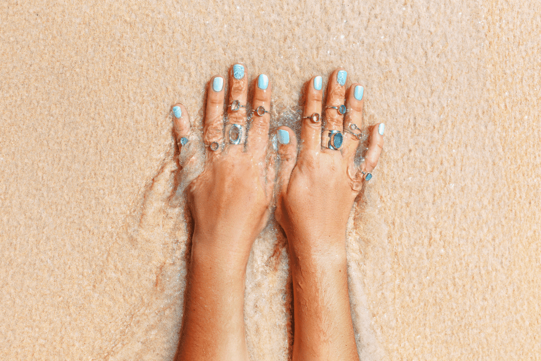 Hand with manicured nails in the sand on the beach