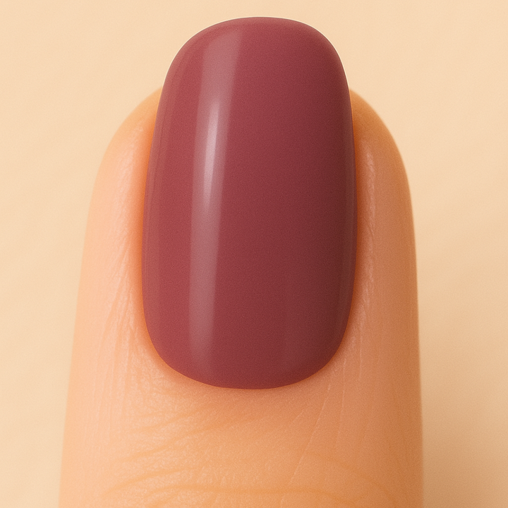 Nail with maroon polish on a beige background