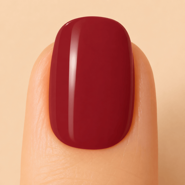 Close up image of a nail with burgundy gel nail polish applied.